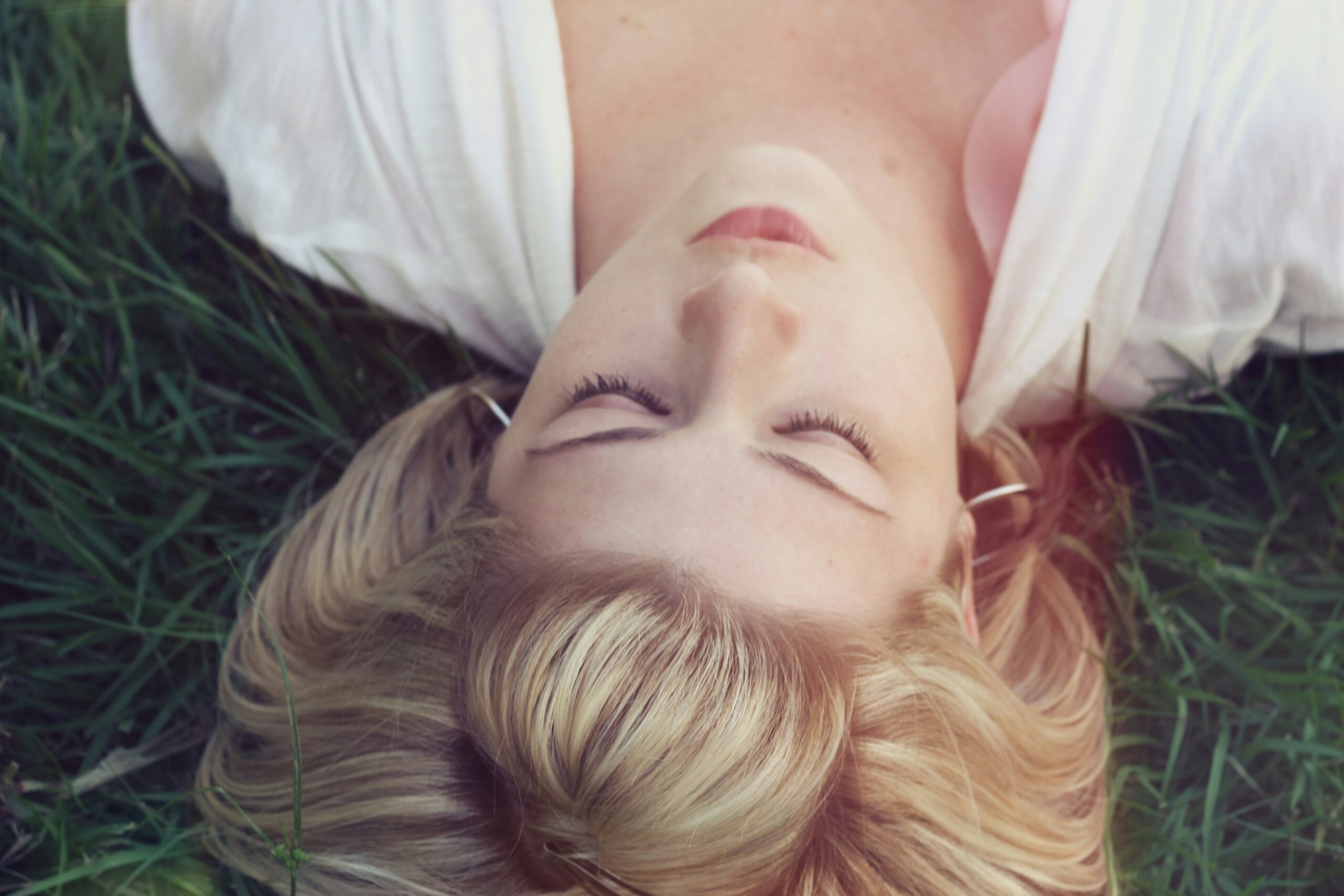 jacob-townsend-OdvNB15f7Uo-unsplash Frau macht liegend eine Atemübung um zu entspannen.